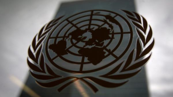 The United Nations headquarters building is pictured though a window with the UN logo in the foreground in the Manhattan borough of New York August 15, 2014. REUTERS/Carlo Allegri (UNITED STATES