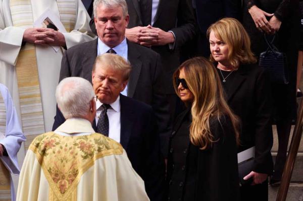 Do<em></em>nald Trump greets a priest in robes beside his wife Melania.