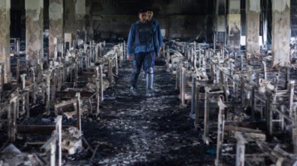 A file photo shows policemen inspecting the charred Tazreen Fashion factory at Ashulia, on the outskirts of Dhaka, in 2012. On 24 November that year, a fire killed 117 and injured more than 200 in the factory with poor fire safety measures. Slow pace of a trial frustrates survivors and rights workers 11 years after the accident. Photo: Courtesy